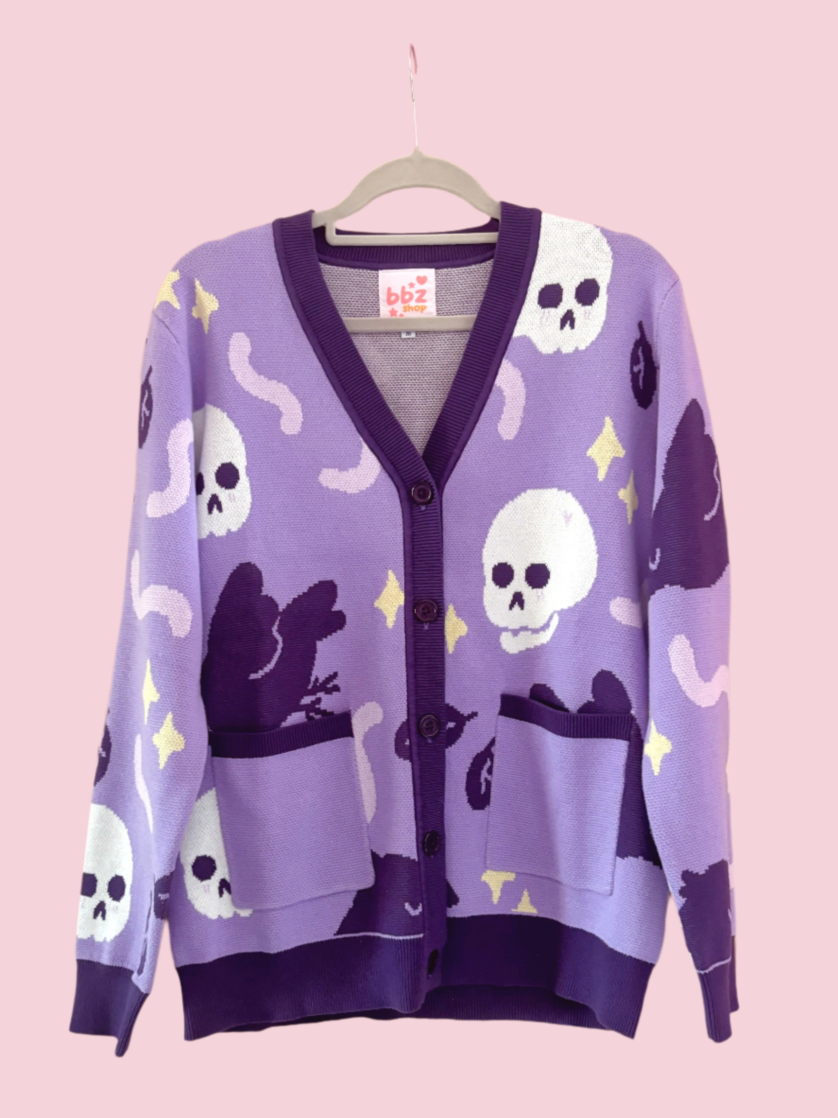 A purple cardigan with a pattern of black ravens and skulls 